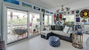Ein gemütliches Wohnzimmer mit einer Eckcouch, einem runden Couchtisch und einem großen Fenster mit Blick ins Freie.