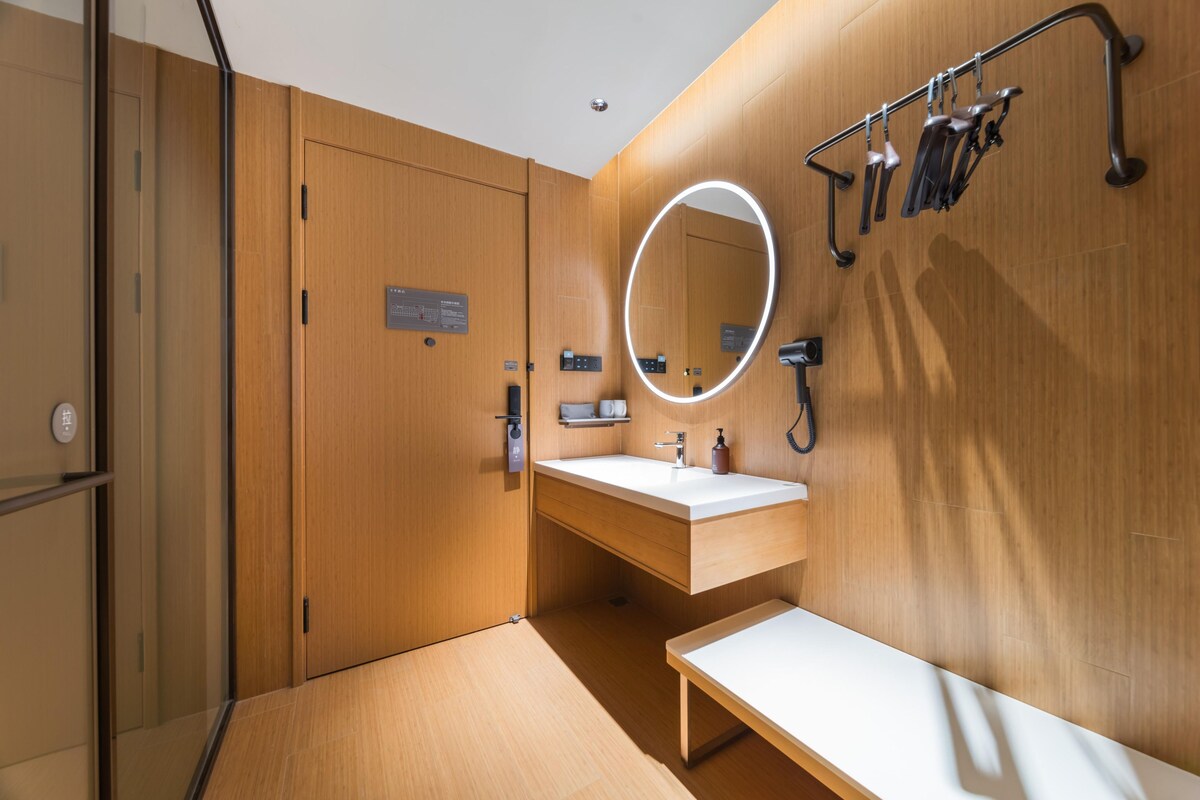 Ein modernes Badezimmer mit Holzwänden, einem weißen Waschbecken, einem Spiegel mit Beleuchtung und einer Bank.