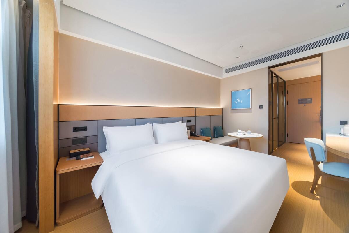Une chambre d’hôtel moderne, dotée d’un grand lit, de tables de chevet, d’un bureau et d’une chaise.