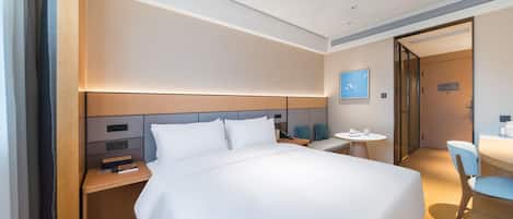Una habitación de hotel moderna con una cama grande, mesitas de noche, un escritorio y una silla.