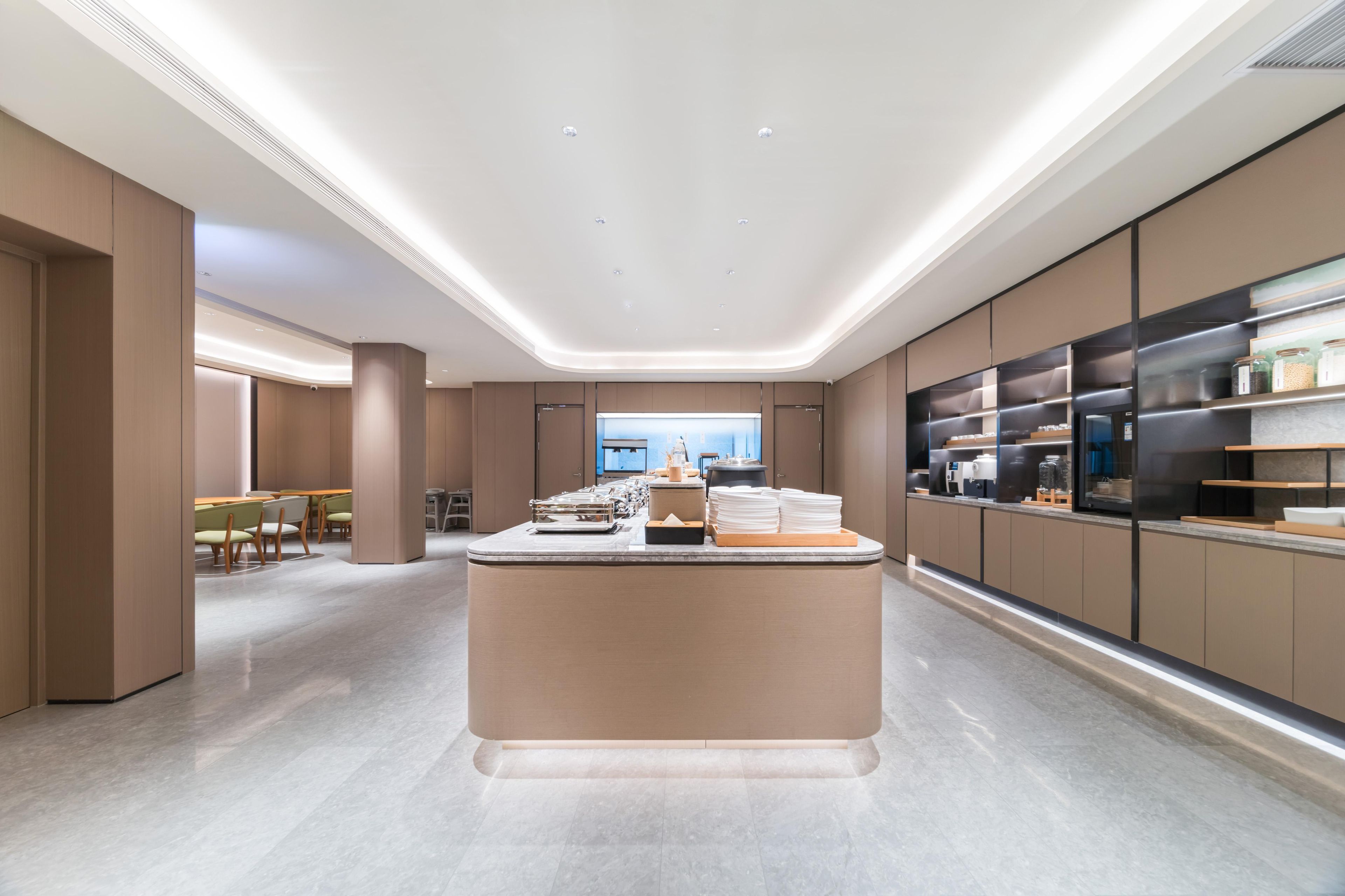 Een moderne hotel lobby met een centraal receptiebalie, een zithoek en een groot raam met uitzicht op de stad.