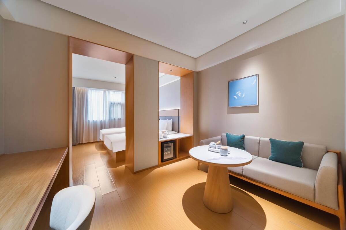 Une chambre d’hôtel moderne avec un canapé, une table basse ronde et un lit doté d’une table de chevet.