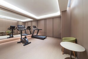 Uma academia moderna com esteiras, uma bicicleta ergométrica e uma pequena mesa.