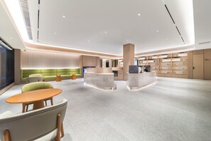 Un hall d’entrée spacieux comprenant un comptoir d’accueil, un espace salon et un grand écran de télévision.