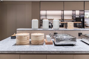 Une cuisine moderne dotée d’appareils électroménagers en acier inoxydable, de boîtes de conservation en bois et d’un plan de travail en marbre.