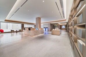 A spacious lobby with a reception desk, seating area, and a display of products. - Ji Hotel Guangzhou Caihongqiao Metro Station (Guangzhou)