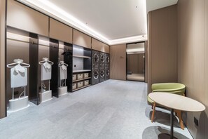 A modern bathroom with a vanity, a sink, and a mirror. There are towels hanging on a rack and a shower area visible in the background. - Ji Hotel Guangzhou Caihongqiao Metro Station (Guangzhou)