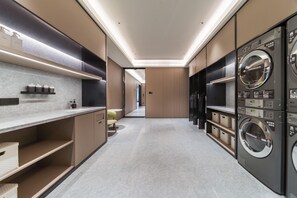 Eine moderne Waschküche mit mehreren Waschmaschinen, einer Theke mit Toilettenartikeln und einem sauberen, gefliesten Boden.
