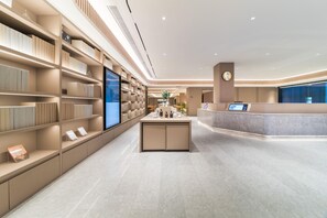 A modern hotel lobby with a reception desk, a large digital screen, and a well-organized bookshelf. - Ji Hotel Guangzhou Caihongqiao Metro Station (Guangzhou)