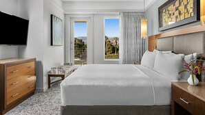A hotel room with a large bed, a TV, a desk, and a view of the outdoors.