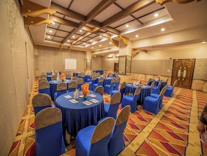 A conference room with round tables, blue chairs, and floral centerpieces.