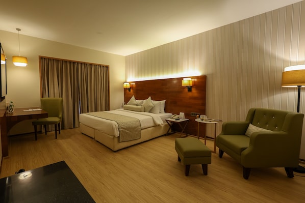 A hotel room with a bed, a desk, a chair, and a sofa.