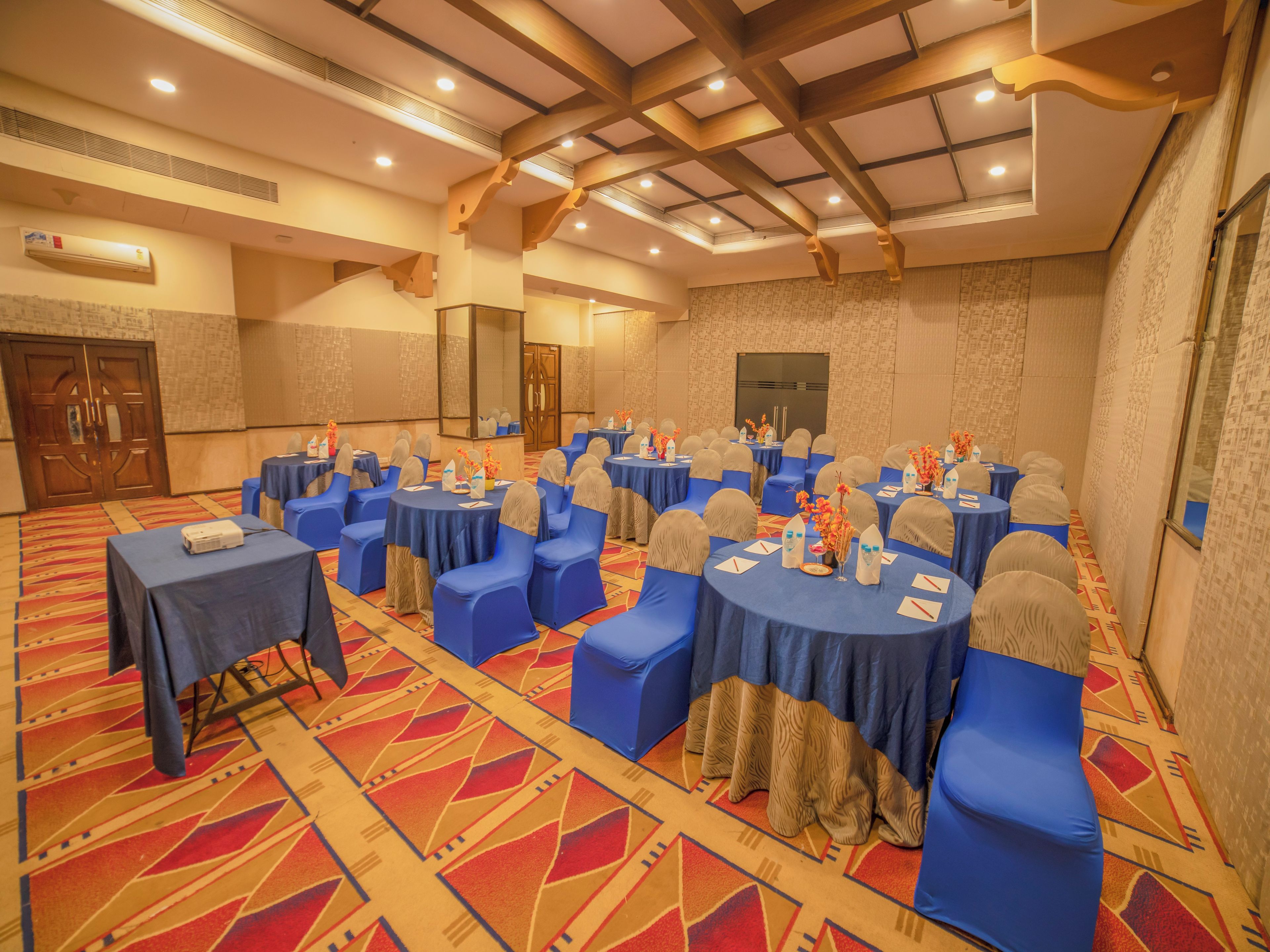 A conference room with round tables, blue chairs, and a patterned carpet.