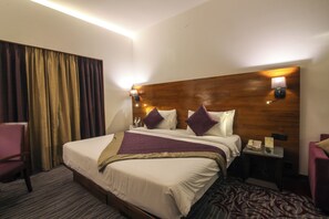 A hotel room with a large bed, two bedside lamps, a wooden headboard, a desk with a telephone, and a chair. - The Orchid Hotel, Pune (Pune)