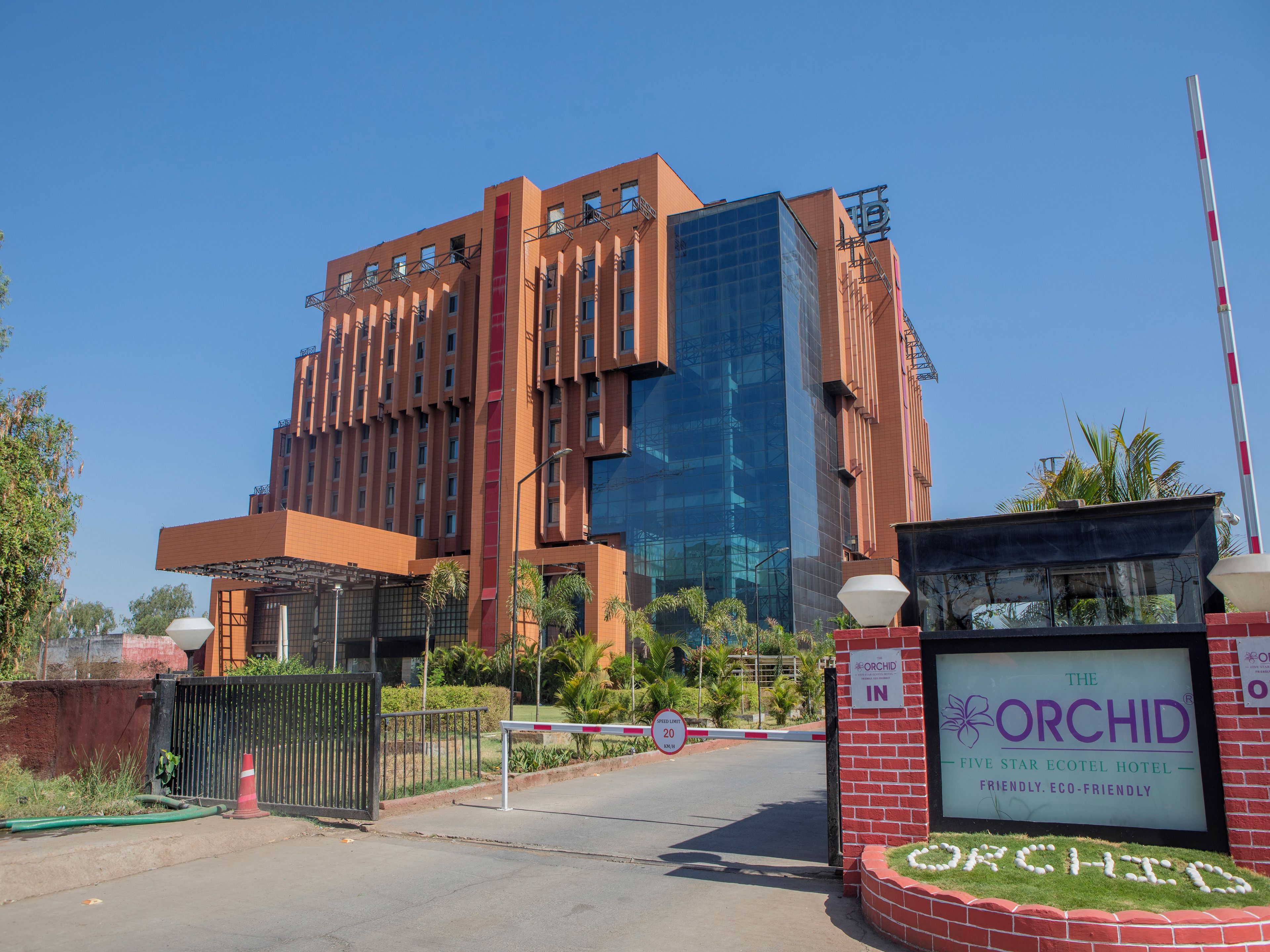 A hotel entrance with a sign for 'The Orchid Five Star Ecotel Hotel' and a speed limit sign of 20 km/h.