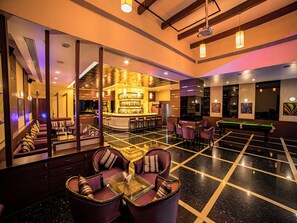 Eine Hotlellobby mit Barbereich, Sitzgelegenheiten und einem Billardtisch.
