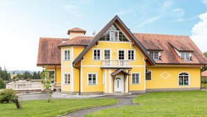A two-story yellow building with a red-tiled roof, a balcony, and a stone pathway leading to the entrance. - Ferienwohnun Stainz 4 Personen (Stainz)