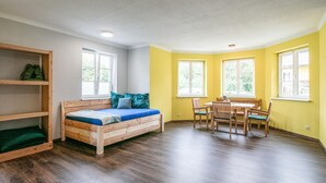 A room with a wooden bed, a dining table with chairs, and a bookshelf. - Ferienwohnun Stainz 4 Personen (Stainz)