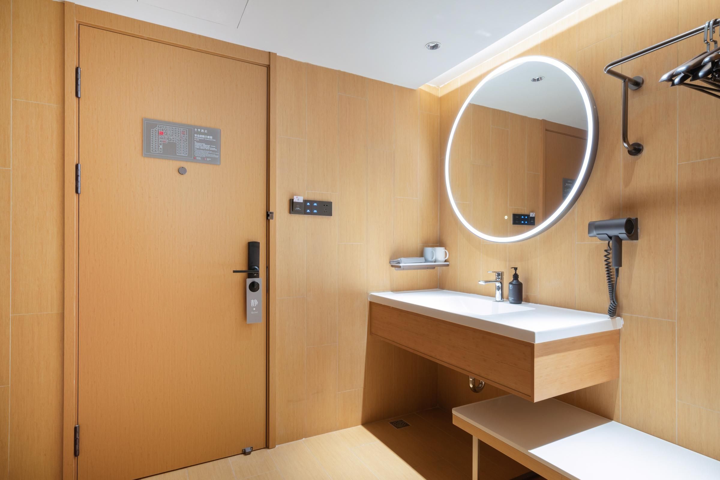A modern bathroom with a wooden door, a vanity with a mirror, and a shower area.
