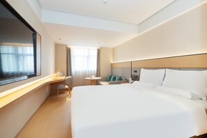 A modern hotel room with a large bed, a desk, a chair, and a small table. - Ji Hotel Guangzhou Jiangtai Road Metro Station (Guangzhou)