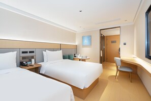 A hotel room with two beds, a desk, a chair, a small table, and a nightstand with a phone and remote control. - Ji Hotel Guangzhou Jiangtai Road Metro Station (Guangzhou)