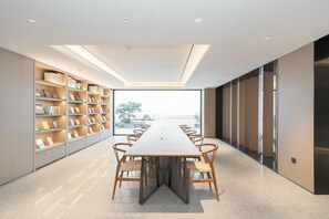 A modern meeting room with a long table, chairs, and bookshelves. - Ji Hotel Guangzhou Jiangtai Road Metro Station (Guangzhou)