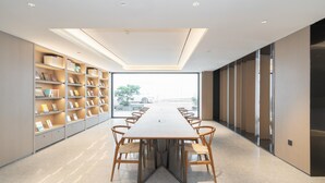 Une salle de réunion moderne, dotée d’une longue table, de chaises et d’étagères.
