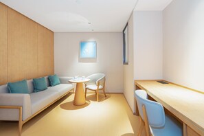A modern, well-lit room with a sofa, two chairs, a small round table, and a desk. - Ji Hotel Guangzhou Jiangtai Road Metro Station (Guangzhou)