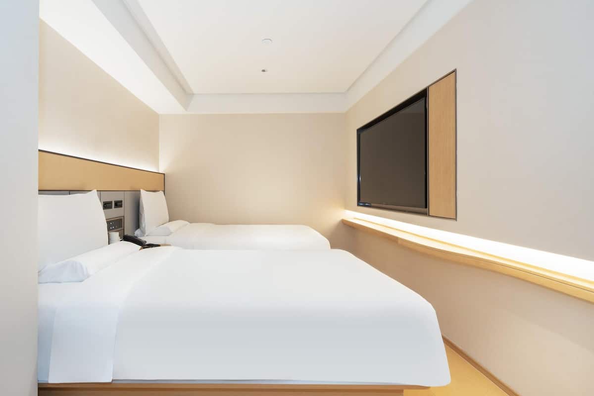 Una habitación de hotel con cama, mesita de noche y televisión montada en la pared.