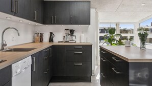 Una cocina moderna con armarios oscuros, un lavavajillas Bosch, una cafetera y una ventana con vistas a zonas verdes.