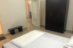Un dormitorio moderno con cama, armario y una banca.