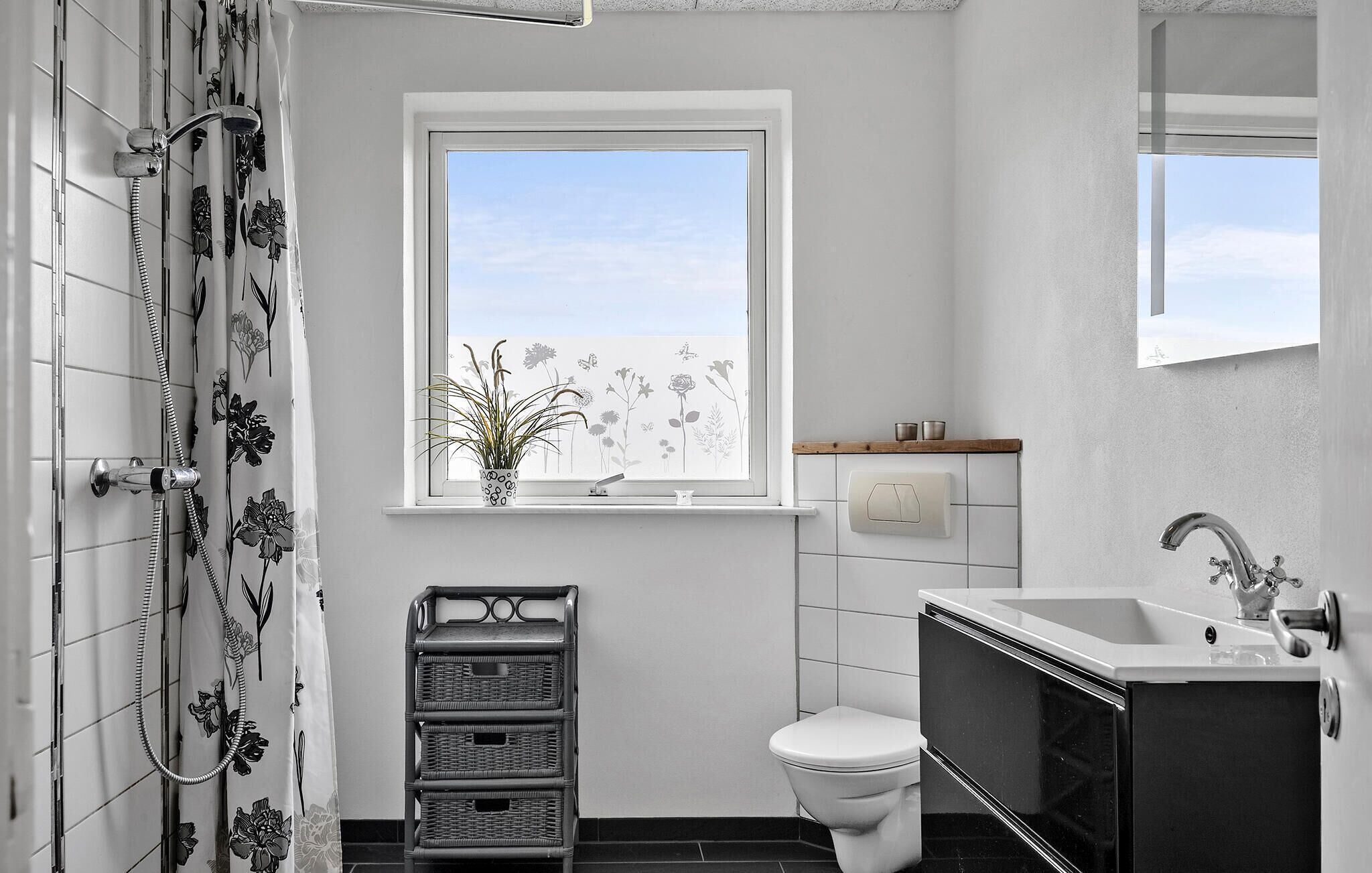 Une salle de bain comprenant des toilettes, un lavabo, une douche, une fenêtre avec vue et une plante en pot.