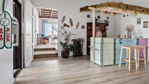 A cozy interior with a wooden floor, a rustic bar area, and a seating area with a view to the outside.