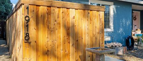 A wooden fence with the number 918, a concrete planter, and a house with a blue exterior and a white window.