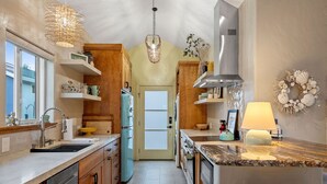 A kitchen with wooden cabinets, a built-in oven, a sink, and a hanging light fixture.