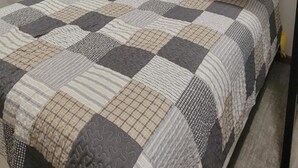 Un lit superposé avec une couvre-lit matelassé, un ventilateur de plafond et une table de chevet avec une lampe.