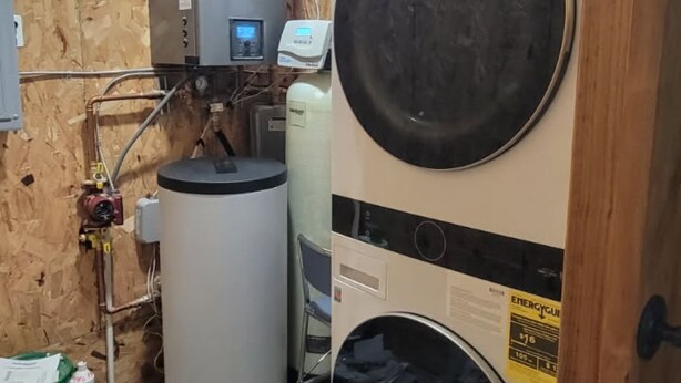 Une pièce équipée d’un chauffe-eau, d’un grand réservoir d’eau et d’un lave-linge.