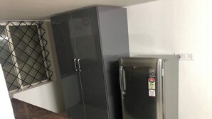 A kitchen with a refrigerator, a cabinet, and a window with a metal grid. - Z2 - Maison de ZEN 2, For Serenity, Bliss & Relaxation (Murugeshpalya)