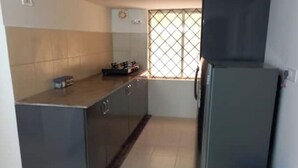 A compact kitchen with a refrigerator, a sink, and a window with a grid pattern. - Z2 - Maison de ZEN 2, For Serenity, Bliss & Relaxation (Murugeshpalya)