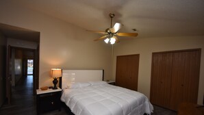 Ein Hotelzimmer mit einem Bett, einem Nachttisch mit Lampe, einem Deckenventilator und Holzschränken.