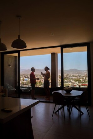 A modern interior with a large window, a dining area, and a kitchen counter.