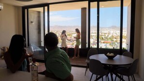 A modern dining area with a large window overlooking a cityscape. - Ocean's Point by Baja Toms (Cabo San Lucas)