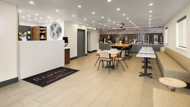 Un hall d’hôtel moderne comprenant un comptoir d’accueil, un espace salon et une kitchenette.