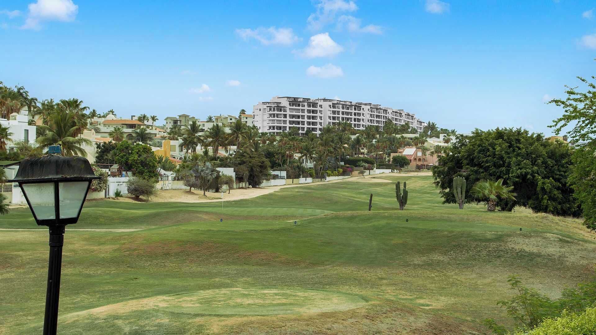 Un terrain de golf avec un lampadaire, des cactus et, au fond, un grand bâtiment d’hôtel.