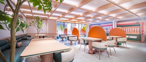 A modern interior with a long table, orange chairs, and a green sofa.