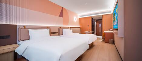 A modern hotel room with two beds, a small bedside table, a wall-mounted TV, and a bathroom visible through an open door.
