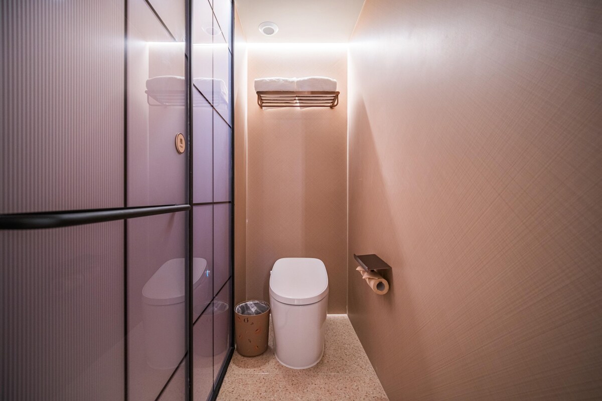 Um banheiro compacto com vaso sanitário, lixeira e porta-toalhas.