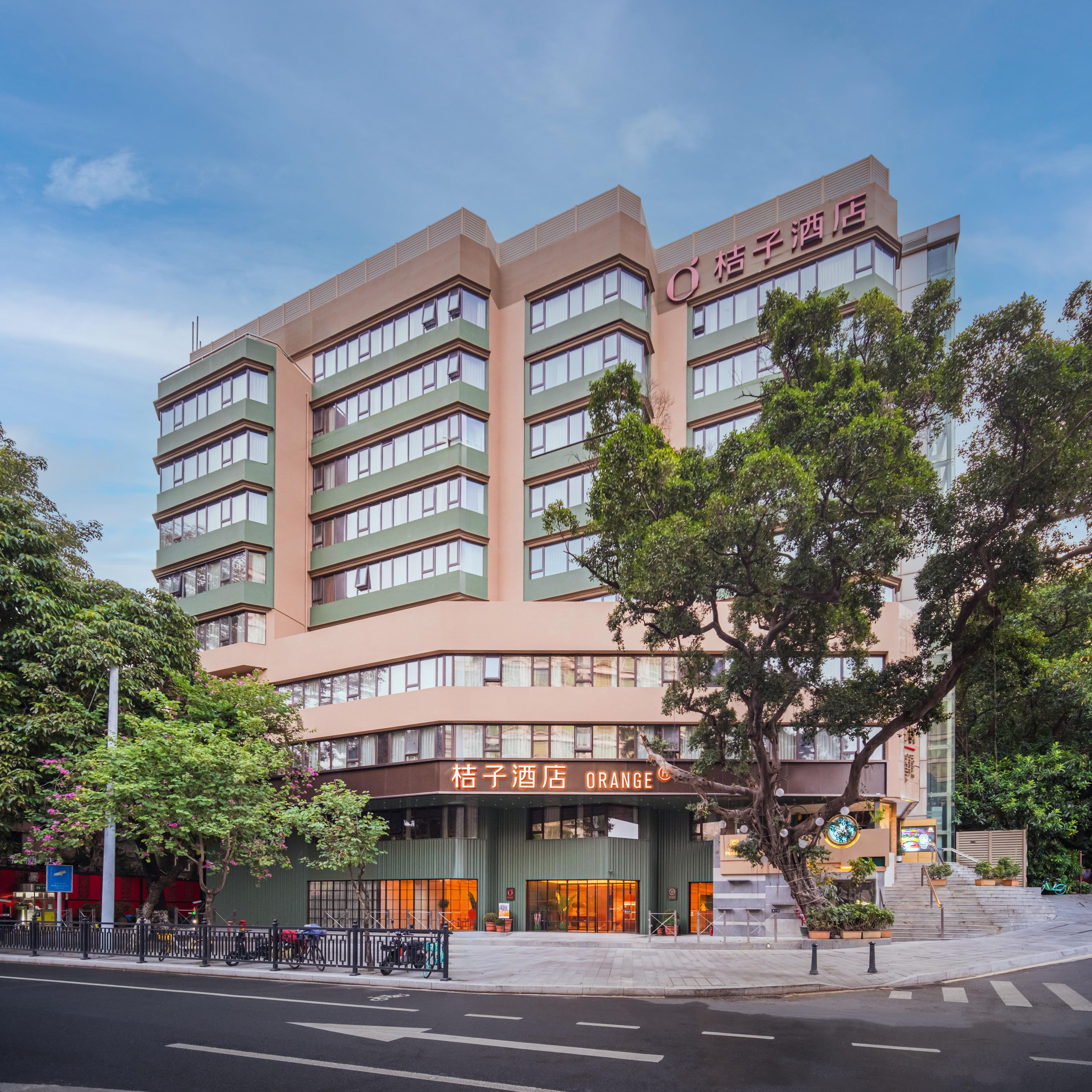 Um hotel com vários andares e design moderno, com uma placa laranja grande na entrada.