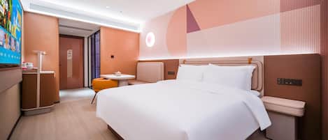 Una habitación de hotel moderna con una cama grande, mesitas de noche, una pequeña zona de estar y un televisor.