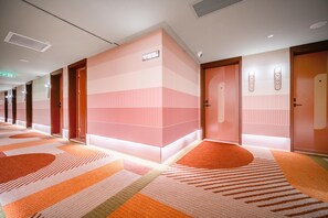 A hotel corridor with a modern design, featuring a patterned carpet, multiple doors, and a bright ceiling light. - Orange Hotel Guangzhou Yuexiu Park (Guangzhou)